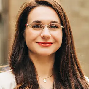 Woman with long brown hair wearing thin rimless glasses