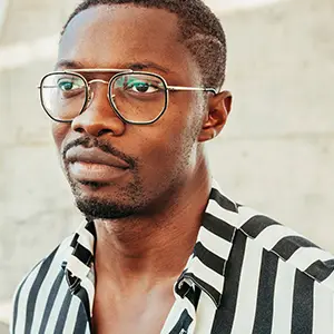 Man in a striped shirt wearing clear metal aviator-style glasses