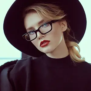 Woman in a wide-brimmed black hat wearing black rectangular glasses