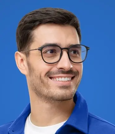 Smiling man in a blue jacket wearing round dark-framed glasses